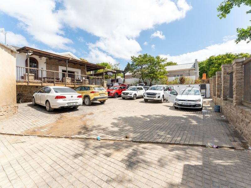 Commercial property exterior featuring a paved parking area, stone boundary walls, and a raised timber deck entrance.