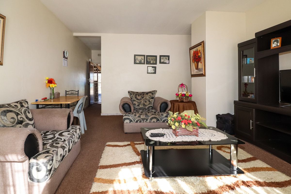 A living room area featuring carpeted flooring and neutral wall finishes, providing a functional space for relaxation and dining.