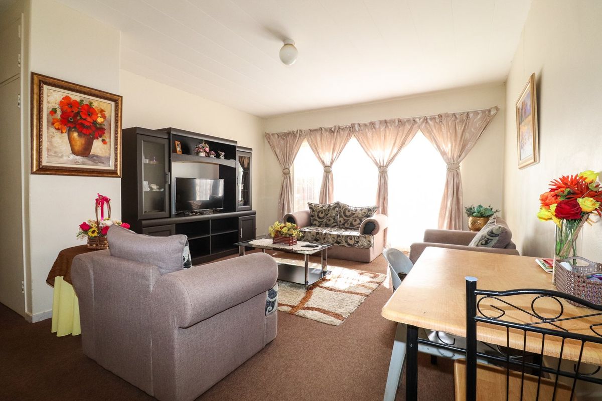 A functional living room area featuring a large window that provides natural light, suitable for a comfortable seating arrangement.