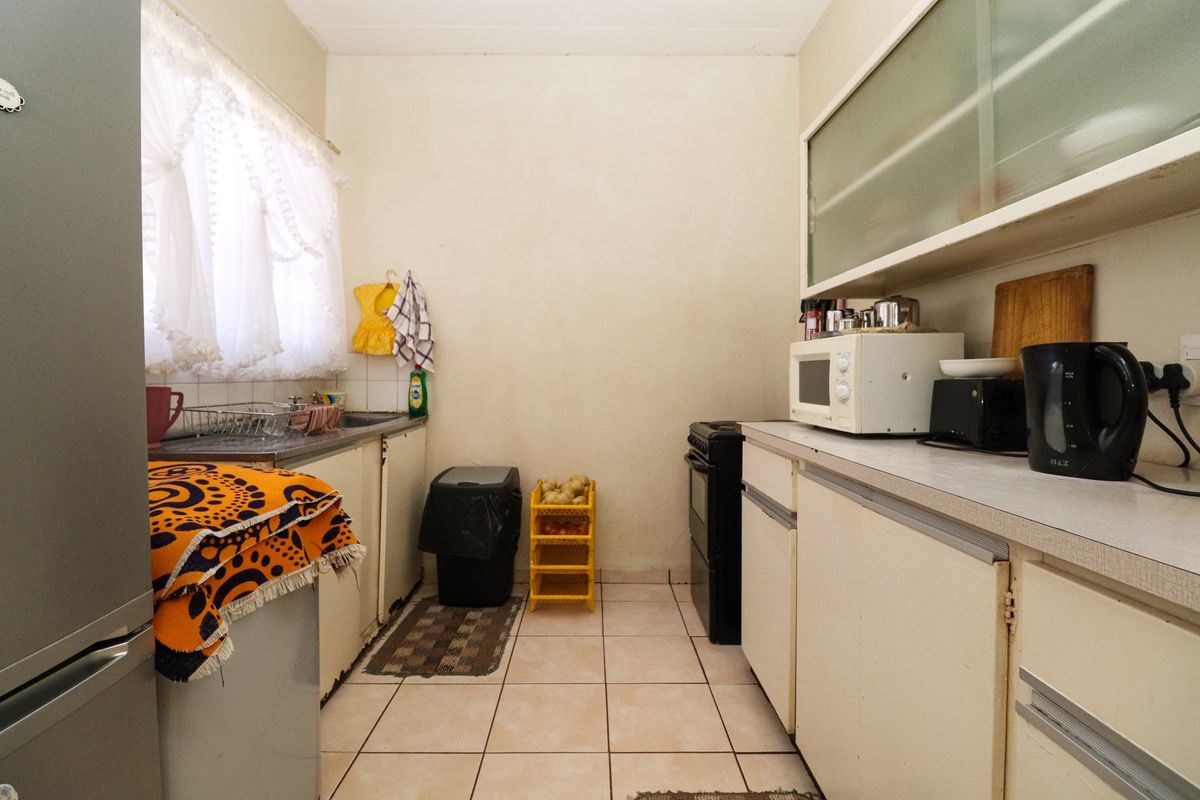 A functional kitchen featuring tiled flooring, laminate countertops, and built-in cabinetry, offering a dated aesthetic ready for modernization.