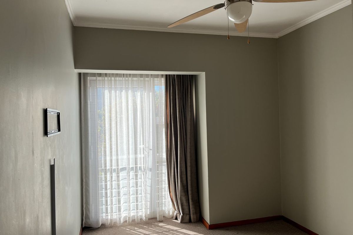 A vacant bedroom featuring neutral wall tones, carpeted flooring, a ceiling fan, and a sliding glass door providing access to an outdoor area.