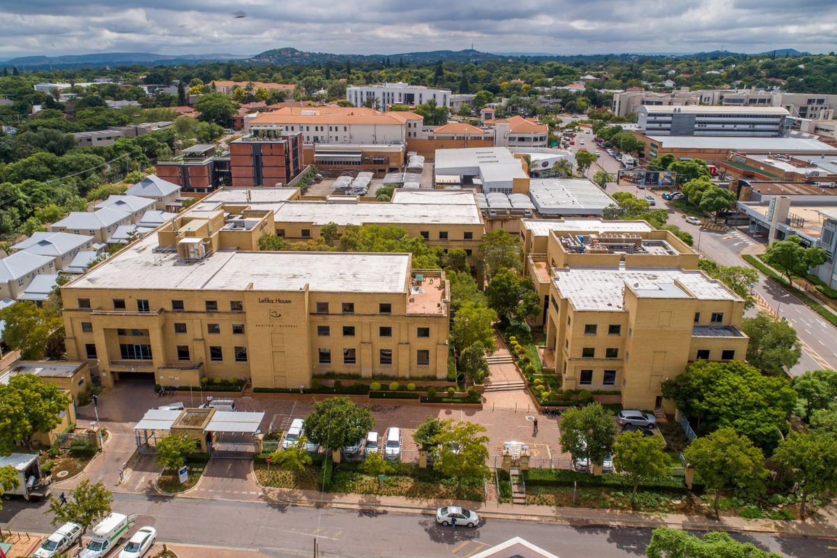 Aerial view of a multi-story commercial office complex featuring brick facades, flat roofing, and dedicated on-site parking facilities within a landscaped urban setting.