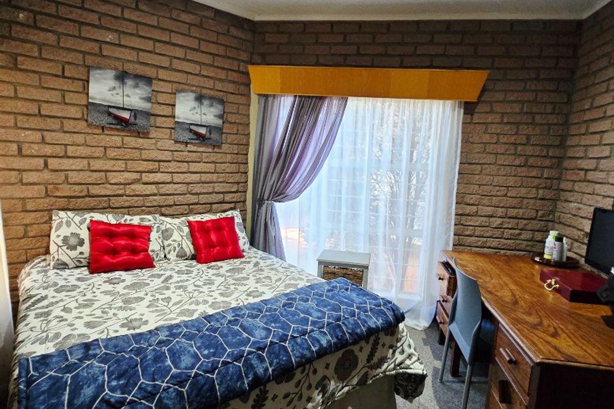 A bedroom featuring exposed brick walls, a tongue and groove ceiling with recessed lighting, and carpeted flooring.