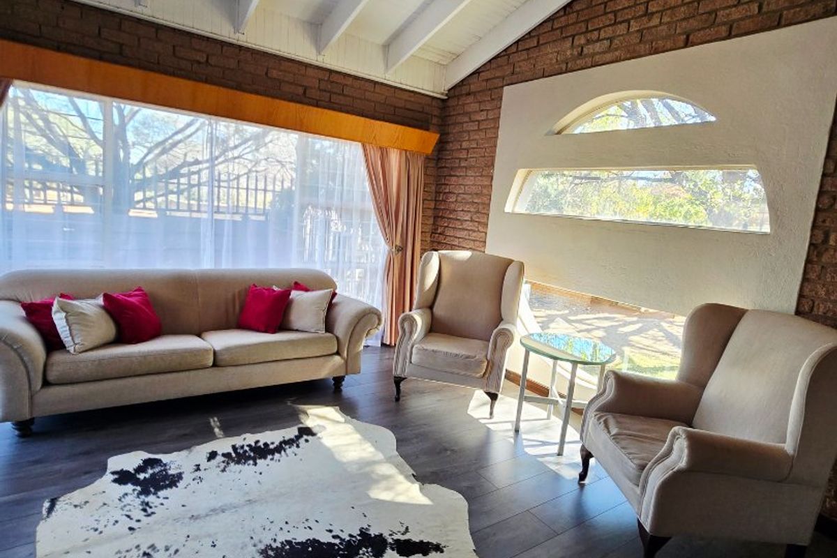 Spacious living room featuring exposed brick walls, high vaulted ceilings with exposed beams, laminate flooring, and unique decorative arched windows.