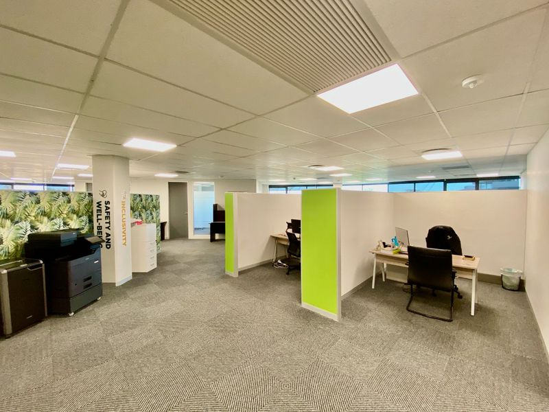 Open-plan commercial office space featuring modular partition walls, carpeted flooring, and a suspended ceiling with integrated lighting.