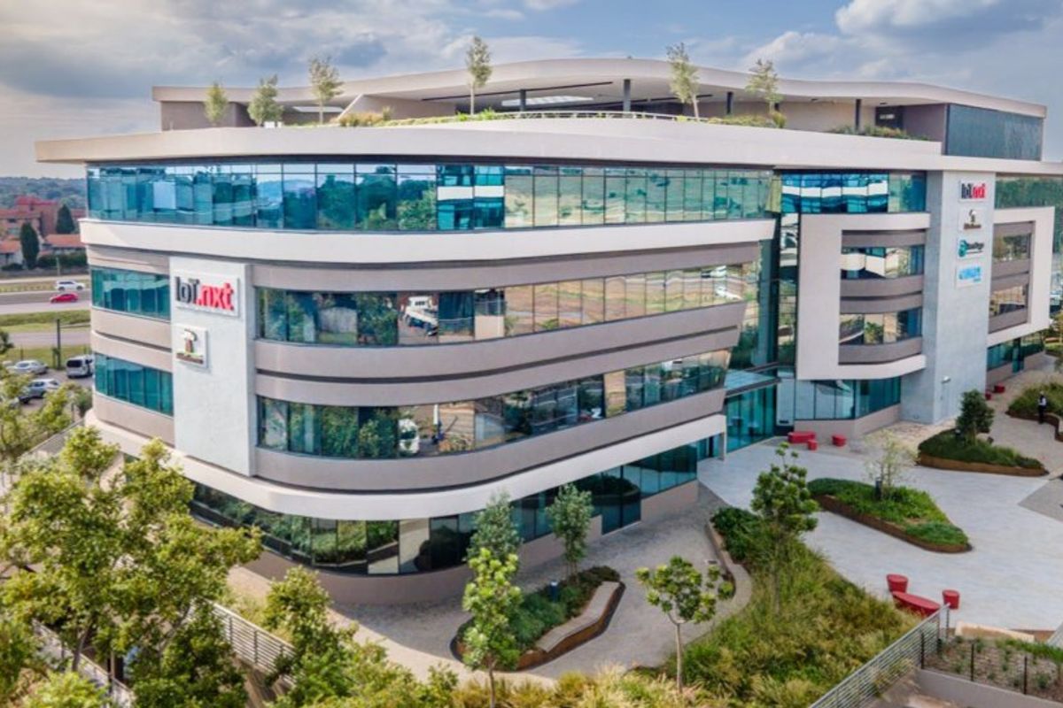 Aerial view of a modern multi-story commercial office building featuring a glass facade, landscaped courtyard, and rooftop terrace area.