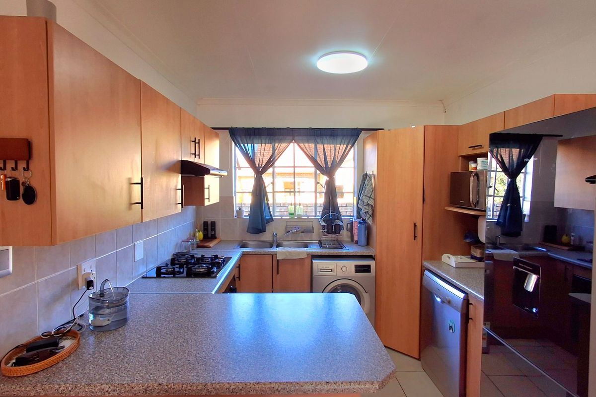 Functional kitchen featuring light wood-finish cabinetry, a gas hob, tiled backsplash, and integrated appliance spaces, offering a practical layout for daily cooking.