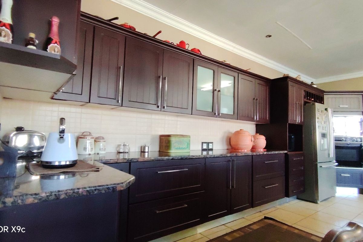 A functional kitchen featuring dark wood cabinetry, granite countertops, and a tiled backsplash, providing ample storage and workspace.