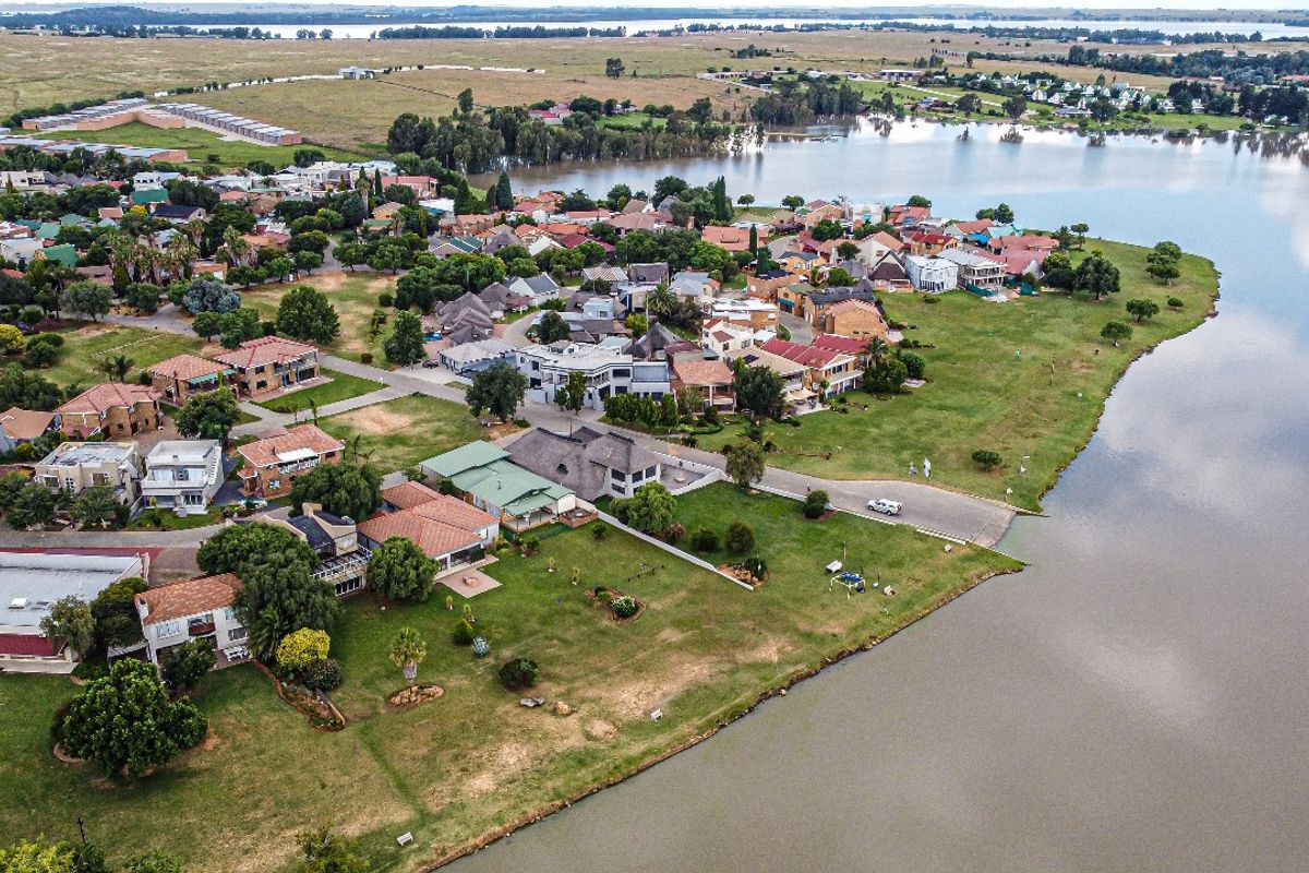 An aerial view of a residential estate situated along a large lake, showcasing the property's location and surrounding landscape.