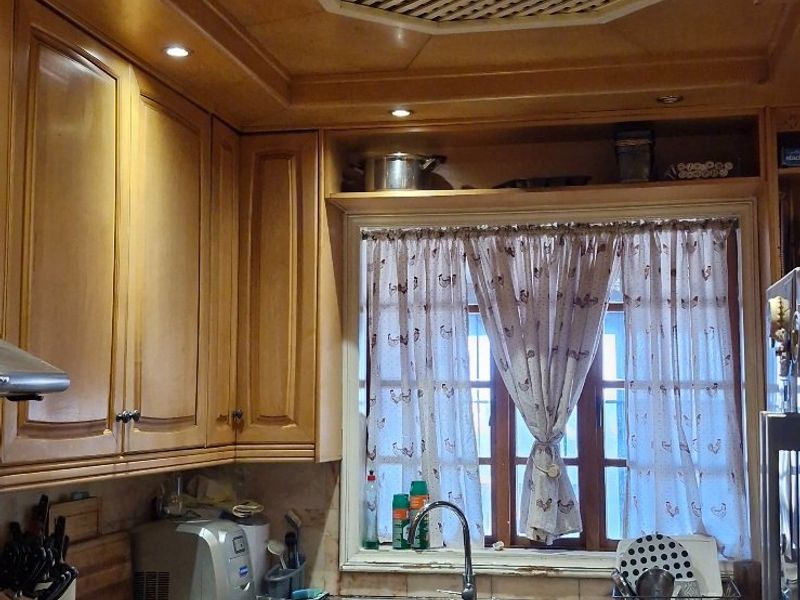 A traditional kitchen featuring wooden cabinetry, granite countertops, a double basin sink, and a unique lattice ceiling detail.