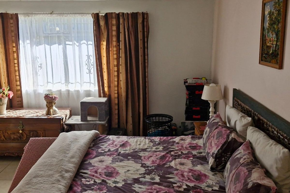 A functional bedroom featuring tiled flooring and a window with curtains, providing a comfortable and well-lit living space.