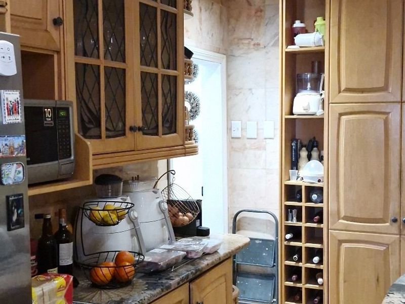 A traditional kitchen featuring timber cabinetry, granite countertops, a built-in wine rack, and stone tile flooring with decorative inlay.