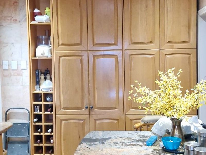 A kitchen area featuring extensive built-in wooden cabinetry, granite countertops, a dedicated wine rack, and decorative recessed ceiling details with integrated lighting.