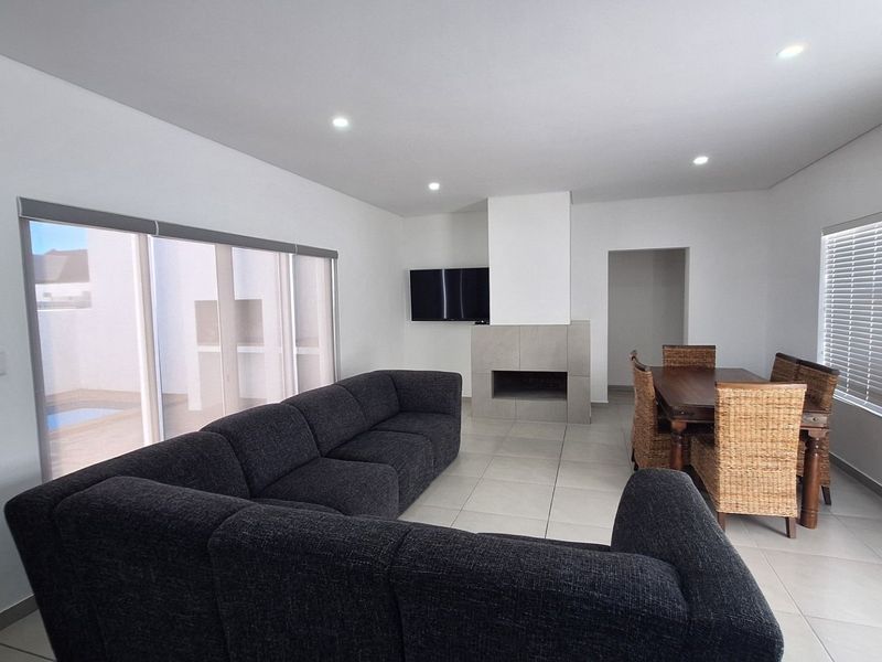 Spacious open-plan living and dining area featuring tiled flooring, a modern built-in fireplace, and large sliding doors providing access to the outdoor patio.