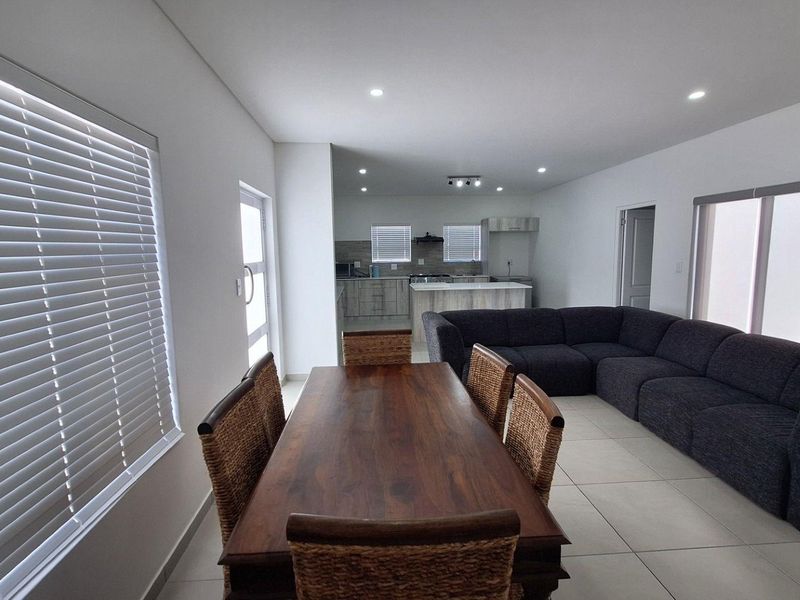 Spacious open-plan living and dining area featuring tiled floors, recessed lighting, and a modern kitchen with a central island and built-in cabinetry.