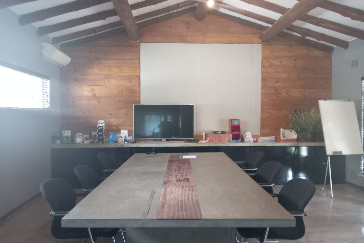 A professional office space featuring exposed timber ceiling beams, polished concrete flooring, and custom built-in cabinetry with a concrete surface.
