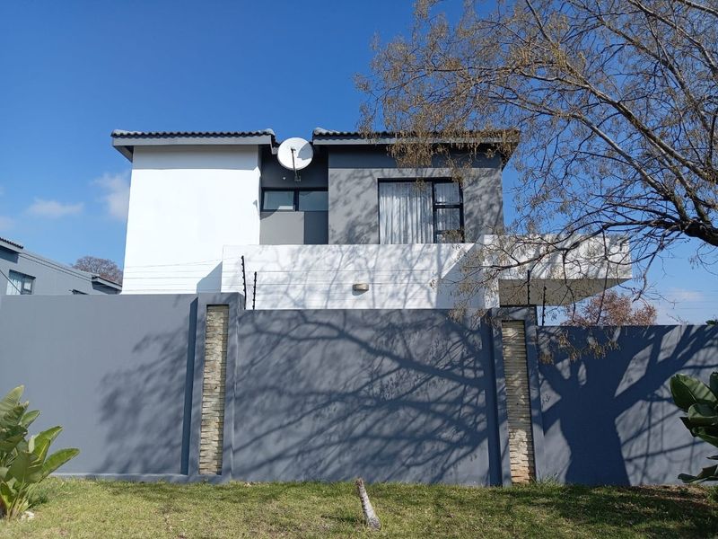 Modern two-story townhouse facade featuring a secure perimeter wall with electric fencing and contemporary grey and white exterior finishes.