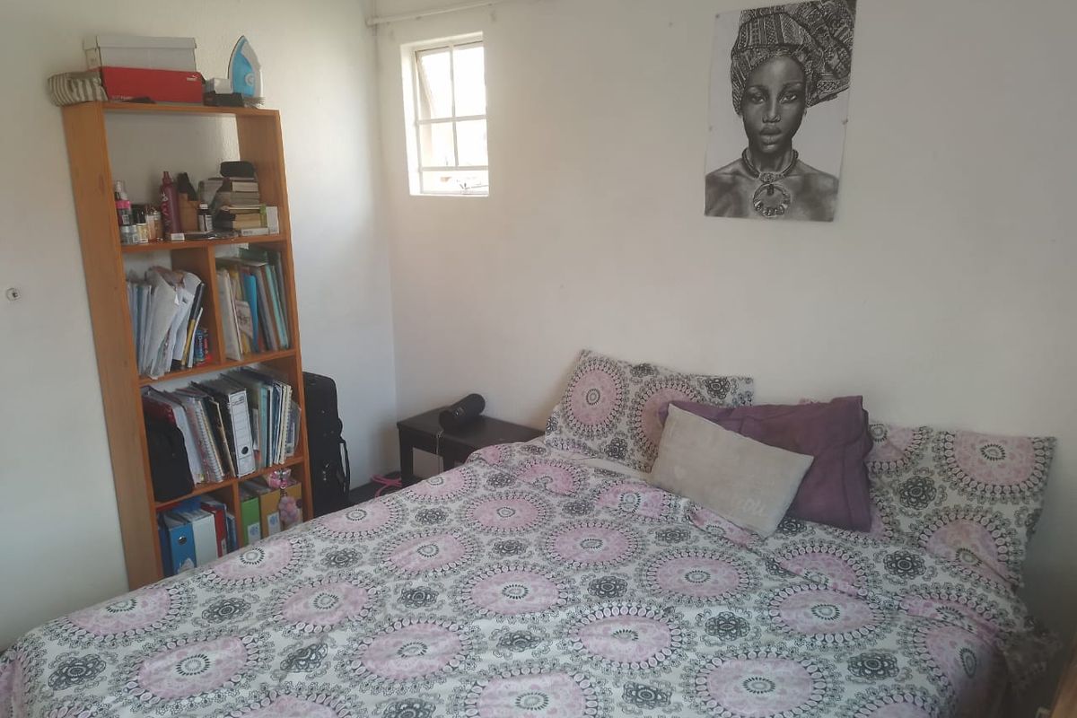 A functional bedroom featuring a small window and ventilation grille, providing a simple and compact living space.