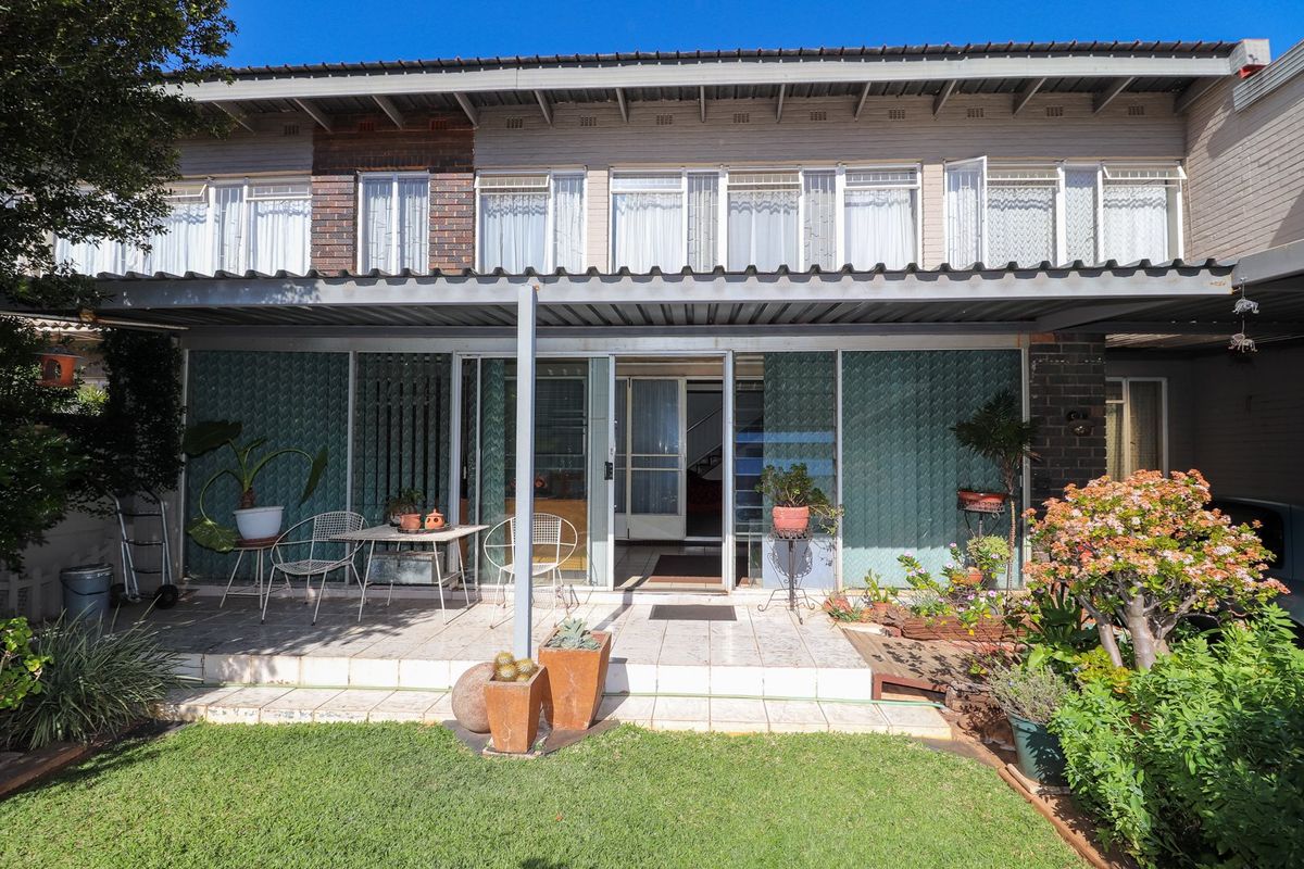 Rear view of the apartment featuring a tiled patio area, sliding glass doors, and a small private garden space.