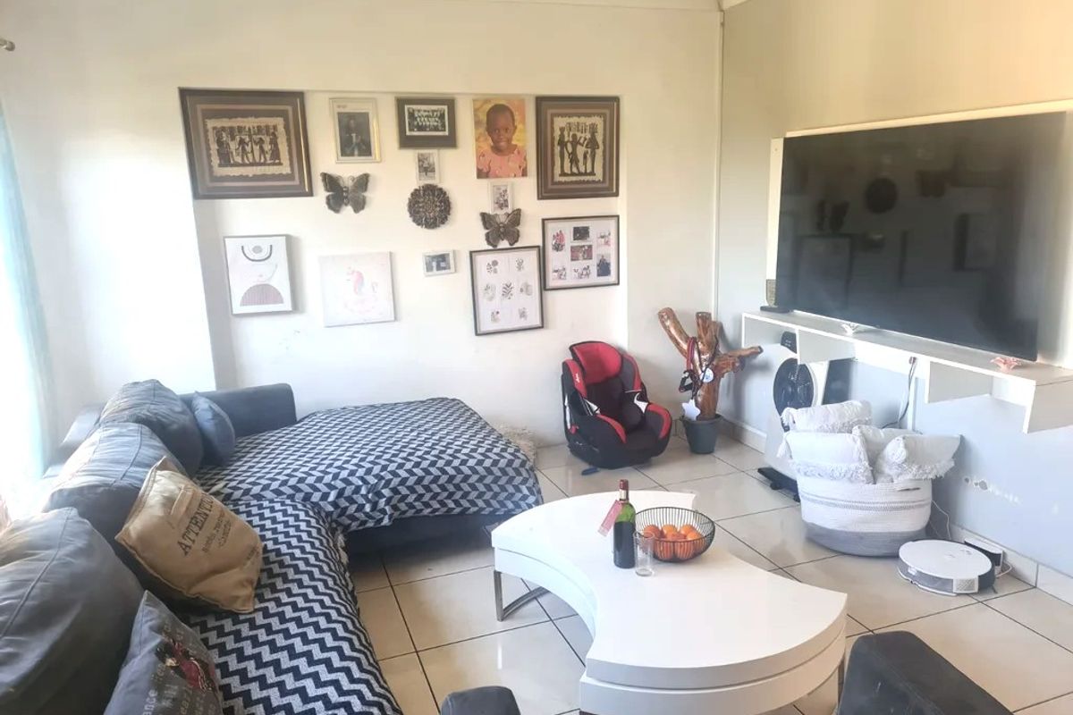 A comfortable living room featuring tiled flooring, recessed lighting, and a wall-mounted media console, providing a functional space for relaxation.