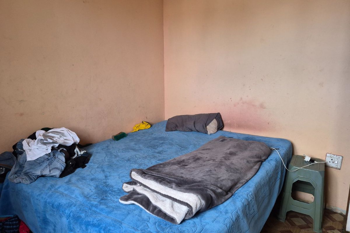 A bedroom featuring plain walls with visible surface wear and staining, requiring cosmetic updates to improve the overall condition.