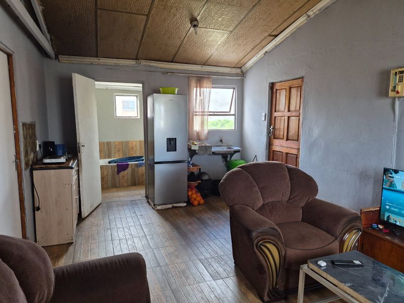 Open plan living area featuring tiled flooring, timber ceiling, and a basic kitchen sink area with direct access to an adjacent bathroom.