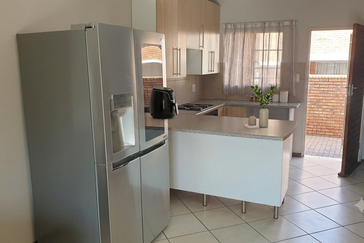 A functional kitchen featuring laminate cabinetry, tiled flooring, and direct access to an outdoor area, providing a practical layout for daily use.