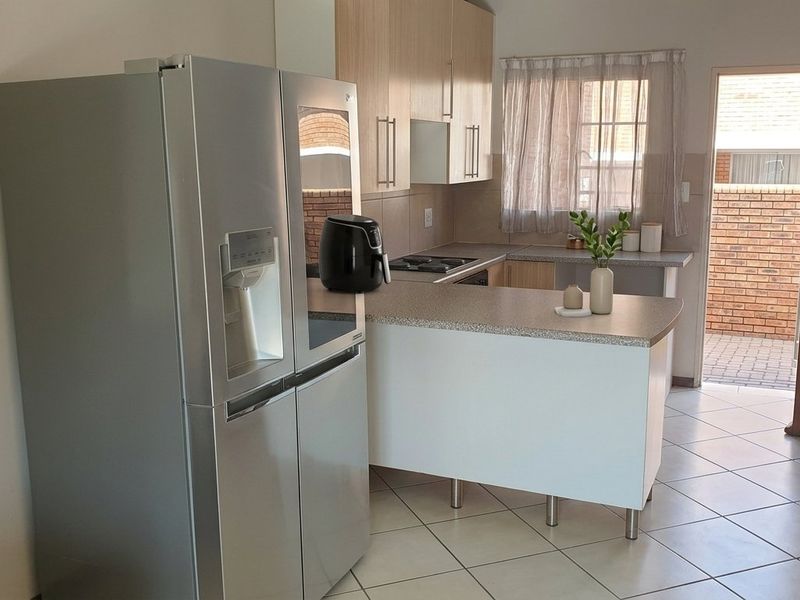 A functional kitchen featuring laminate cabinetry, tiled flooring, and direct access to an outdoor area, providing a practical layout for daily use.
