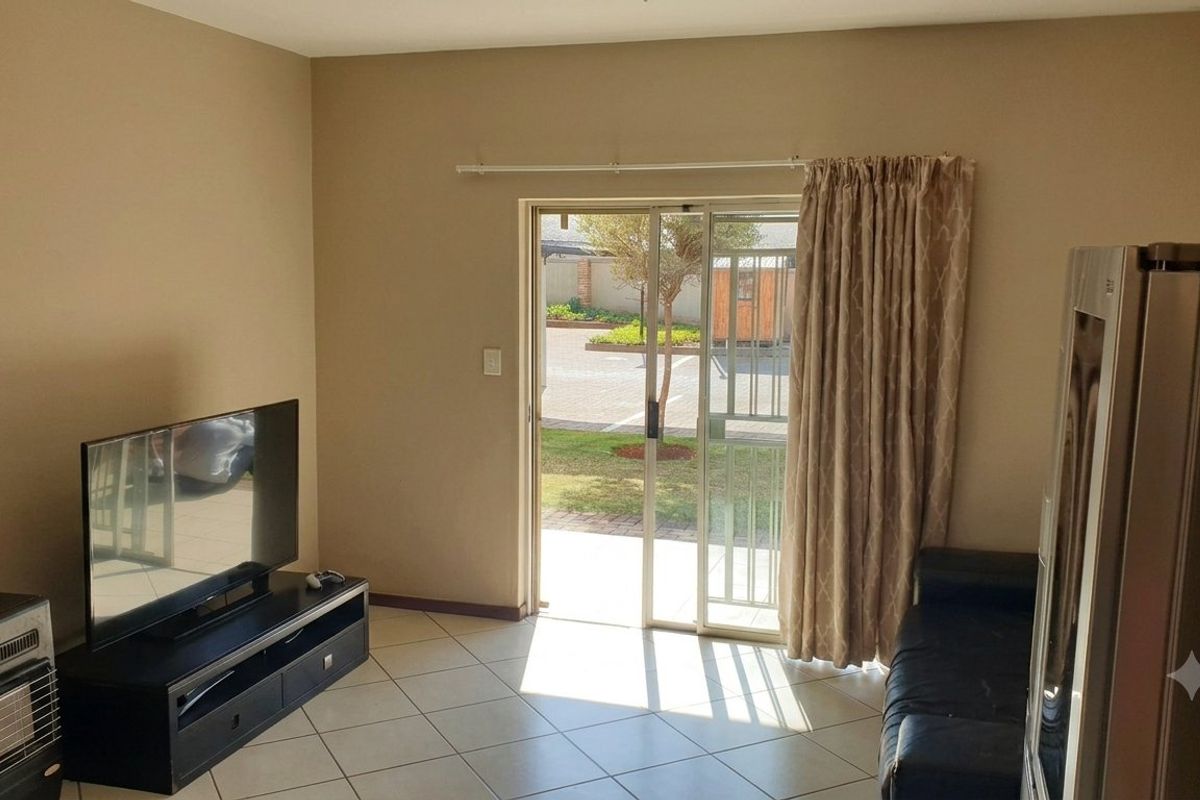 Living room featuring ceramic floor tiles and a sliding glass door with security gate providing direct access to the exterior.