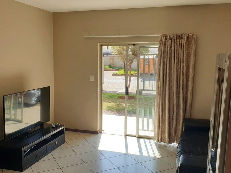 Living room featuring ceramic floor tiles and a sliding glass door with security gate providing direct access to the exterior.