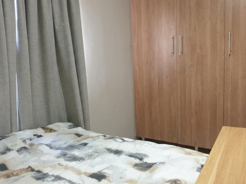 A bedroom featuring a light wood-finish built-in wardrobe and neutral wall tones.