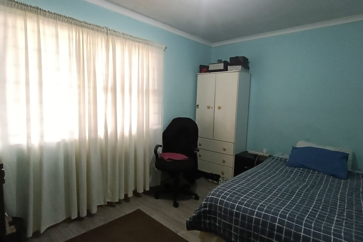 A functional bedroom featuring light blue walls, laminate flooring, and a coved ceiling, providing a neutral base for personalization.
