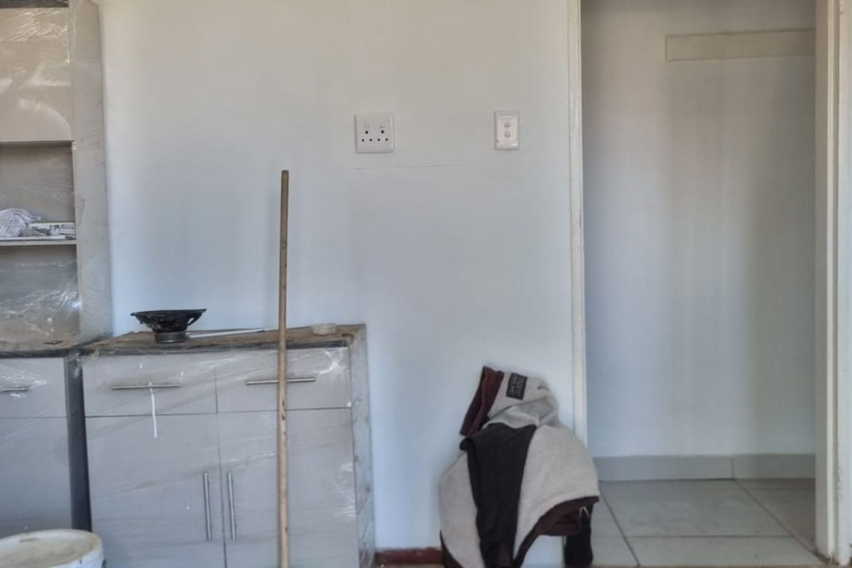 A kitchen area featuring newly installed cabinetry with protective film still attached, awaiting final completion and finishing touches.