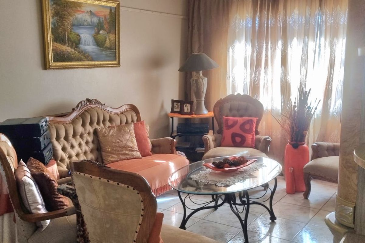 A traditional living room featuring tiled flooring and large windows with curtains, offering a comfortable and functional space for relaxation.
