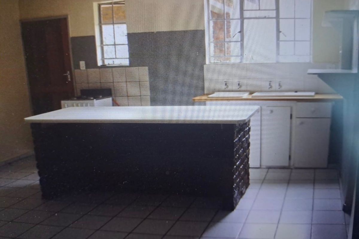 A dated kitchen featuring a central island, double sink, tiled flooring, and built-in cabinetry, offering significant potential for a modern renovation.