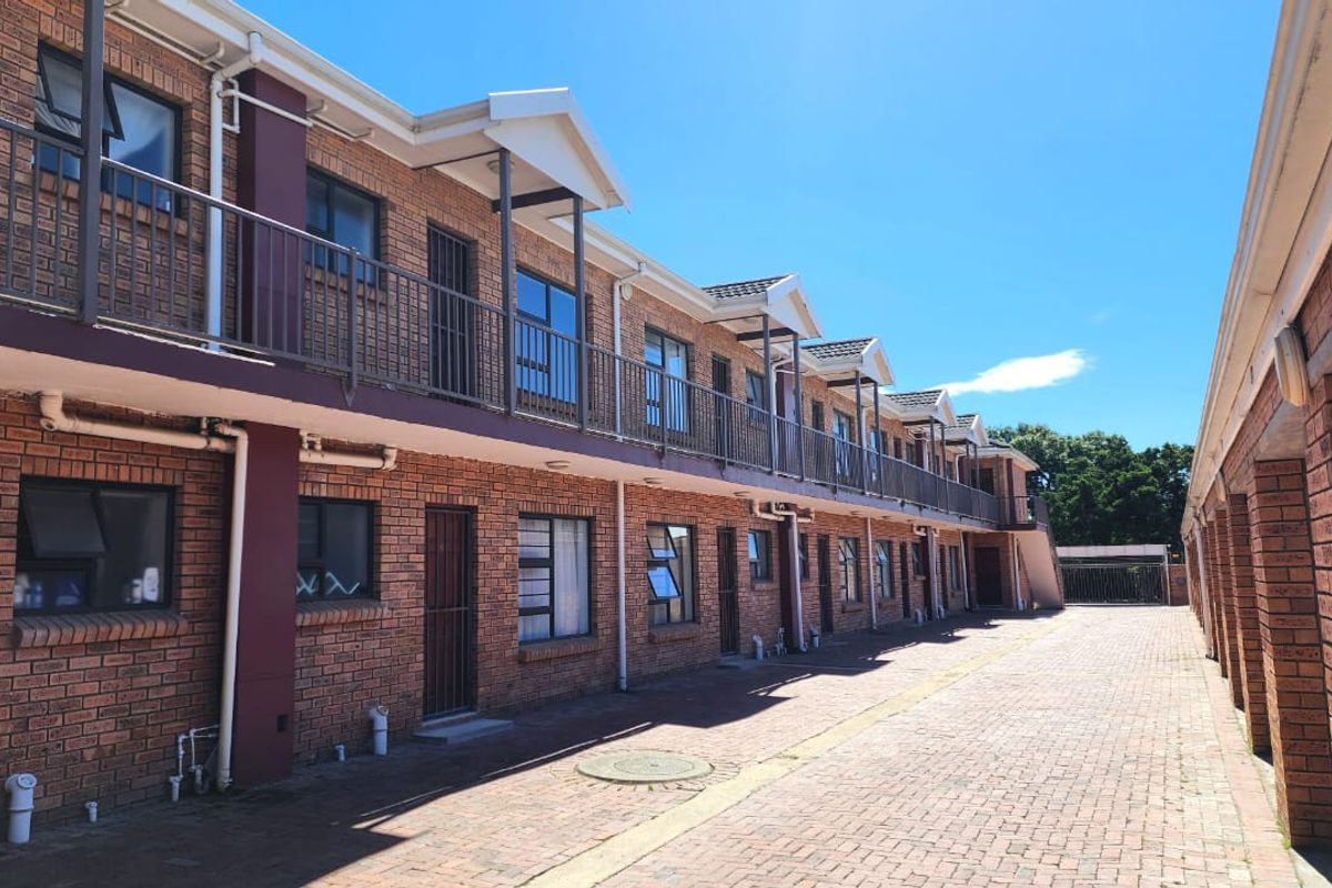 Exterior view of a multi-story apartment complex featuring face brick construction, paved common areas, and metal balcony railings.