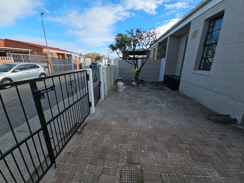 Front exterior view of the property featuring a paved driveway, secure metal gate, and precast boundary walling.