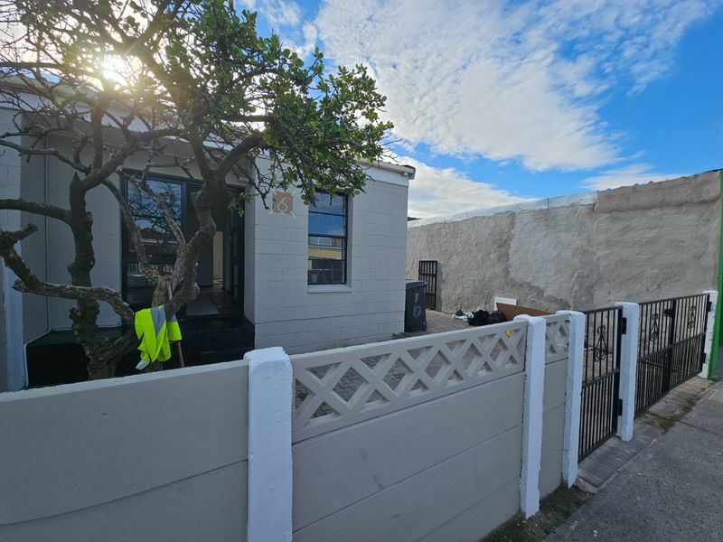Front exterior view of the property featuring a concrete block facade, paved driveway, and secure metal gate entrance.