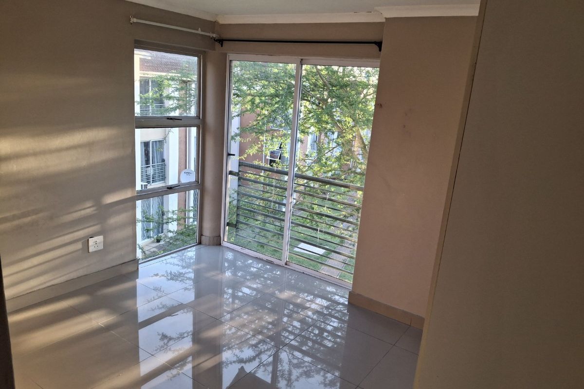 An empty bedroom featuring tiled flooring, a sliding glass door with security bars, and natural light, offering a blank canvas for personalization.