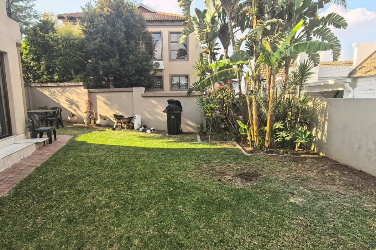 A private rear garden featuring a small lawn area, paved patio section, and perimeter boundary walls.