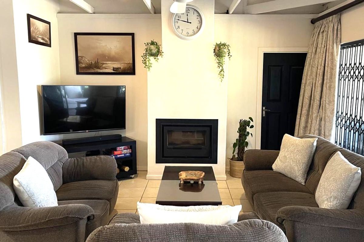 A comfortable living room featuring a built-in fireplace, tiled flooring, and exposed ceiling beams, providing a cozy and functional space.