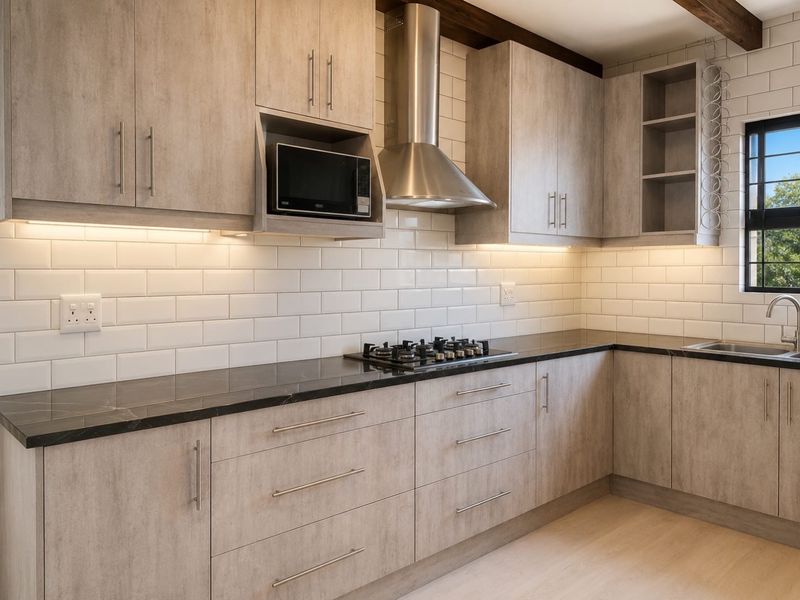 Modern kitchen featuring light wood-grain cabinetry, dark stone countertops, subway tile backsplash, stainless steel appliances, and integrated under-cabinet lighting.