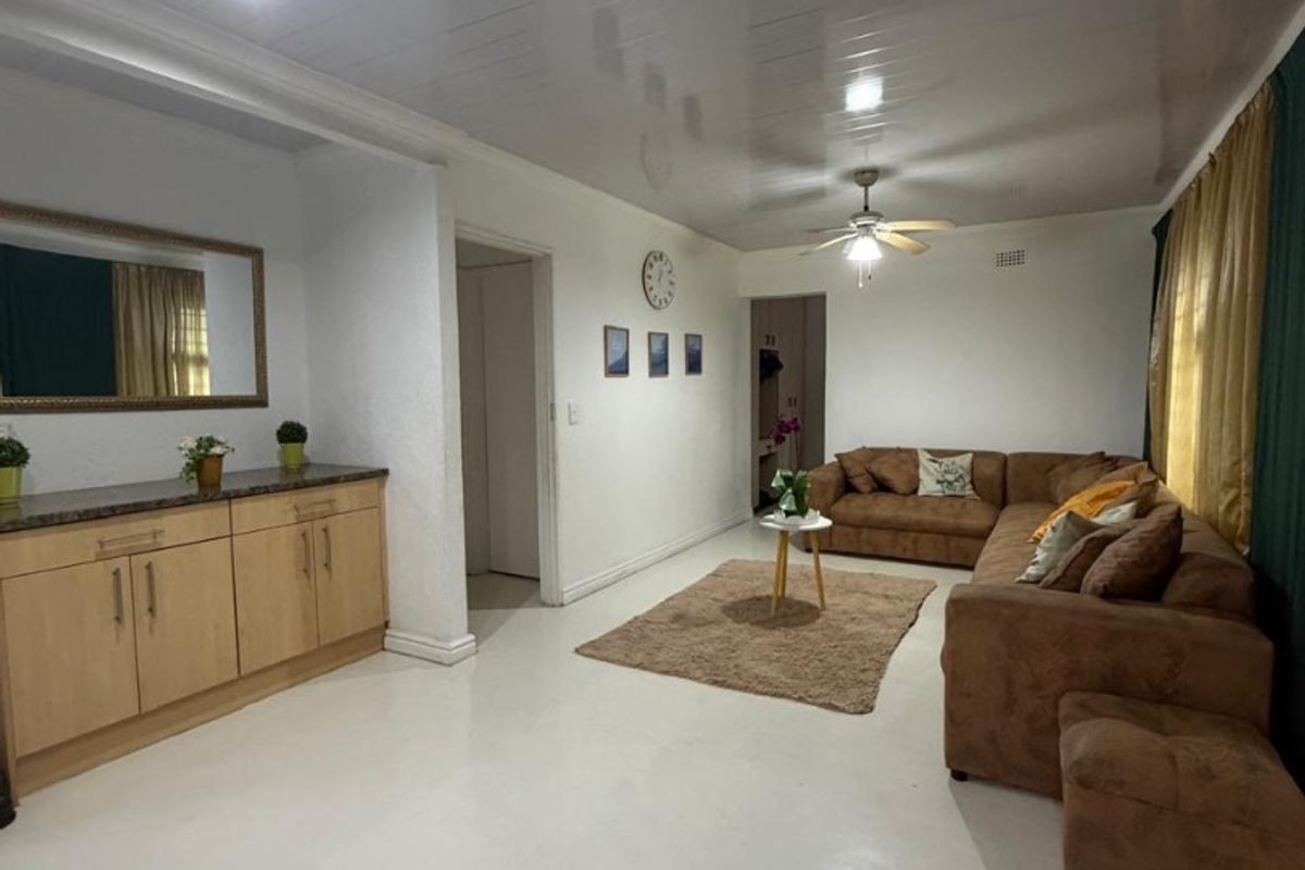 Spacious living room featuring glossy ceiling finish, ceiling fan, and built-in cabinetry with stone-look countertop.