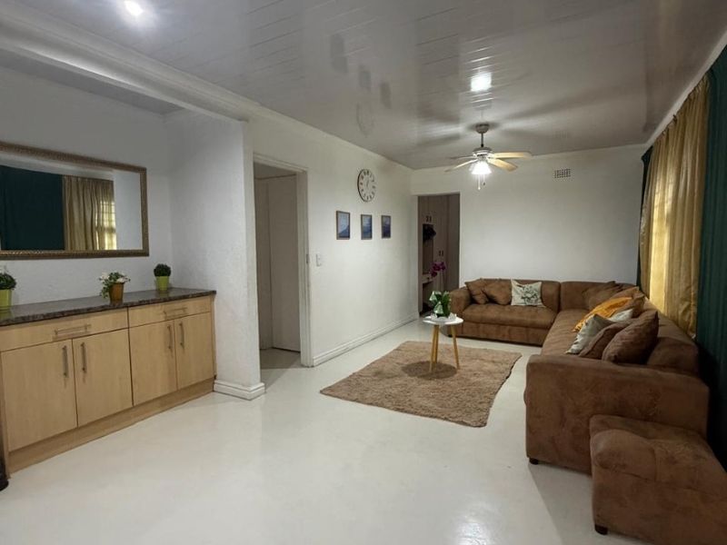 Spacious living room featuring glossy ceiling finish, ceiling fan, and built-in cabinetry with stone-look countertop.
