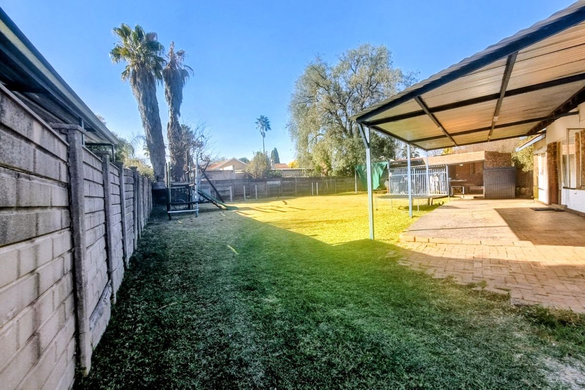 Spacious rear garden featuring a covered patio area, paved flooring, and a secure boundary wall, offering potential for outdoor entertainment and landscaping.