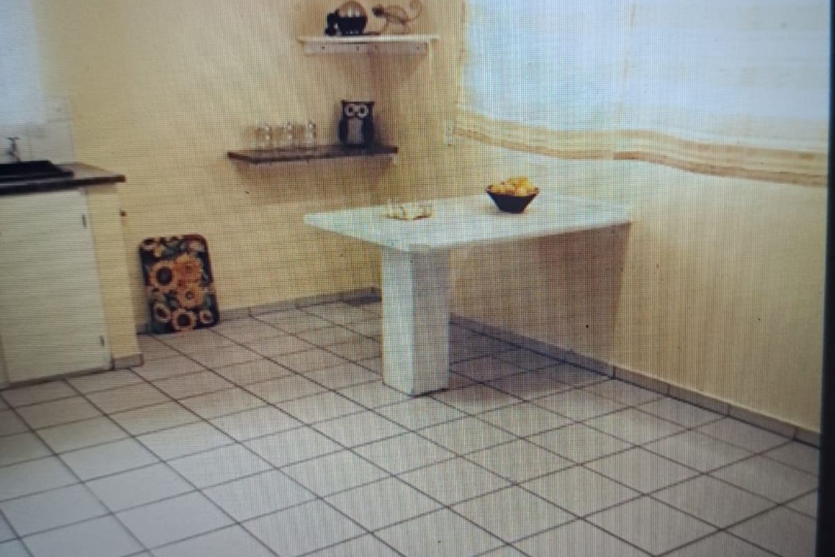 A dated kitchen area featuring tiled flooring, built-in cabinetry, and a fixed breakfast bar, offering potential for a modern renovation.