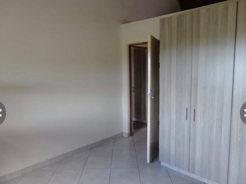 A clean, empty bedroom featuring neutral tiled flooring and modern built-in cupboards, offering a versatile space ready for personalization.