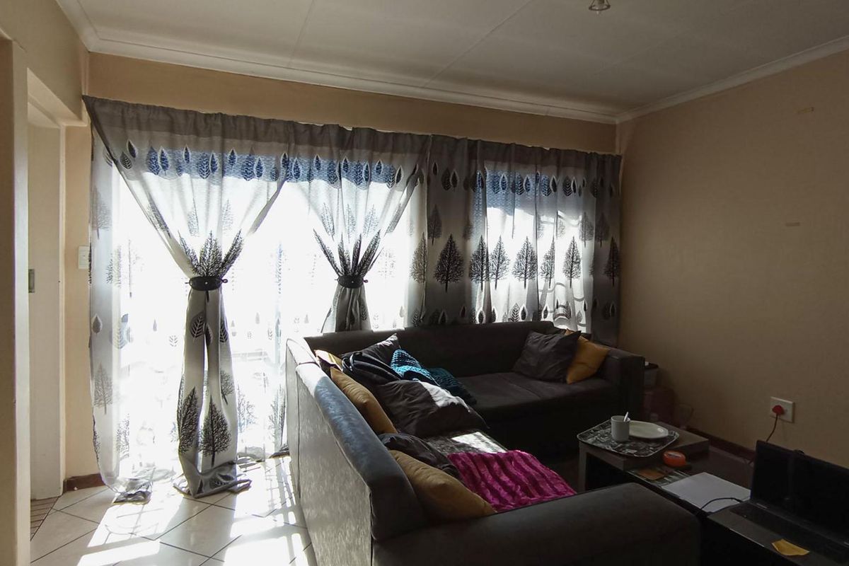 A living room featuring tiled flooring and a sliding glass door providing natural light.