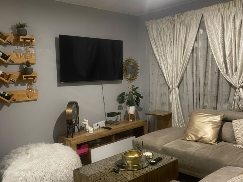 A cozy living room featuring neutral grey walls, recessed ceiling lighting, and large window treatments, creating a comfortable and inviting atmosphere.