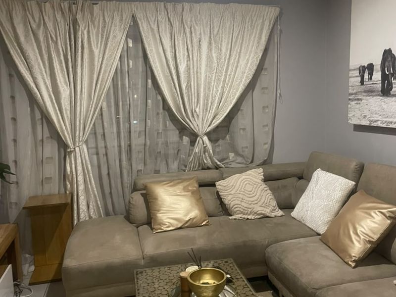 A comfortable living room featuring tiled flooring and neutral wall tones, providing a functional space for relaxation.